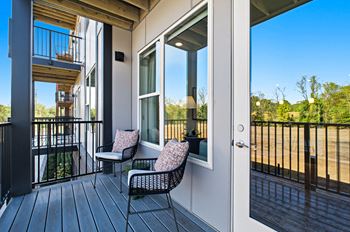 A balcony with a chair and a table with a cushion on it.